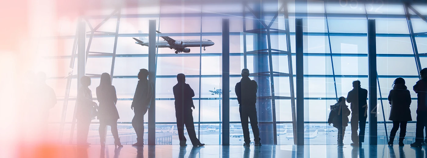 Abflughalle eines Flughafens mit wartenden Menschen und Flugzeug im Hintergrund